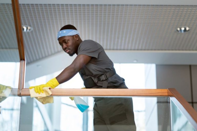Posh Clean staff cleaning glass railings in a commercial office building in Accra